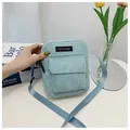 Close-up of light blue corduroy crossbody bag featuring a front pocket and adjustable strap - Blue