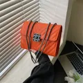 Orange V-quilted crossbody bag with black gemstone buckle and metal chain strap - Orange
