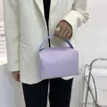 Minimalist lavender square handbag with light blue handles shown on a female model - Purple