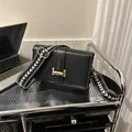 Detalle de bolso bandolera negro con hebilla dorada y correa ancha de diseño geométrico - Negro