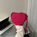 Macro detail of heart-shaped crossbody bag with embossed clover pattern in magenta - Rose Red