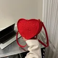 Macro detail of a red heart-shaped crossbody bag featuring stylish clover leaf embossing - Red