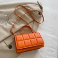 Borsa trapuntata arancione brillante in similpelle con finiture dorate su abito beige - Arancione