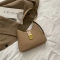 Elegante borsa a secchiello marrone con fibbia in metallo dorato su sfondo bianco letto - Cachi