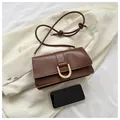 Detail view of a brown vintage leather shoulder bag with gold hardware and phone for scale - Coffee
