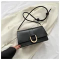 Detail of black leather bag with gold U-shaped buckle on beige blazer background - Black