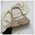 Detailed view of beige baguette bag with matte leather and large buckle on neutral blazer - Khaki