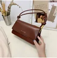Detail der dunkelrotbraunen Ledertasche mit Knotengurten und goldenen Metallakzenten - Dunkelbraun