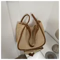 Dettaglio della borsa tote in paglia intrecciata con manici in pelle marrone e rivetti - Marrone