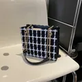 Classic black and white tweed crossbody bag with golden chain strap on a modern chair - Black Grid