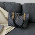 Modische Tragetasche mit blauem Kreuzmuster, Goldkette und Hirschanhänger auf einem Sofa - Schwarz