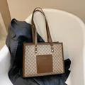 Grote bruine monogram draagtas met voorvak en schouderbanden op een stoel - Khaki