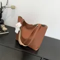 Brown grainy tote bag with white plush bear charm and long straps on a black surface - With Pendant / Brown