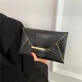 Black crocodile embossed envelope clutch bag with elegant gold metal bar closure - Black