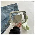 Detail of transparent PVC crossbody bag with mint green trim and heart patch - Green