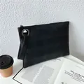 Bolso sobre negro con relieve de cuadros, correa de muñeca y cierre de cremallera - Negro