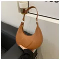 Detailed close-up of brown crescent hobo bag featuring embossed heart pattern and gold zipper - Brown