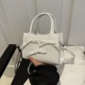 White mini crossbody bag with pearl bow accents and elegant top handles for women - White