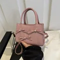 Pink crossbody square bag with decorative bows and pearls on a matte leather surface - Pink