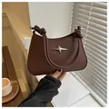 Close-up of dark brown leather crescent bag with star rivet and knotted strap detail - Brown