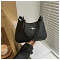 Close-up of matte black underarm bag with silver star buckle and rope handle detail - Black