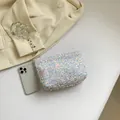 Elegante pochette con paillettes iridescenti e zip metallica su sfondo crema neutro - Bianco