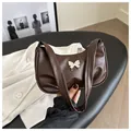Détail de la boucle papillon argentée sur un sac à bandoulière marron foncé pour femme - Brun Foncé