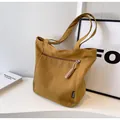 Detail of mustard yellow canvas tote bag featuring front zipper pocket and woven puller - Brown