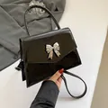 Minimalistische Handtasche aus schwarzem Lackleder mit silberner Schmetterlingsschnalle - Schwarz