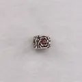 Macro detail of silver floral bead with embossed roses and a purple zircon gemstone - Brown