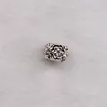 Macro shot of silver petal charm with sparkling center stone on white faux fur background - White