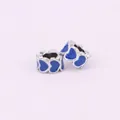 Detail of two silver DIY charms with heart-shaped blue enamel patterns on white background - Blue