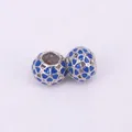 Macro view of silver alloy flower beads with blue enamel hollow heart patterns - Blue
