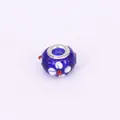 Detailed view of a dark blue glass bead with white floral pattern and silver metal rims - 15x10mm / Blue