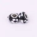 Detailed view of handmade black lampwork glass beads with white 3D floral motifs - 15x10mm / Black