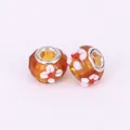 Macro shot of orange glass beads with 3D floral patterns and silver metal core - 15x10mm / Coffee