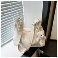 Close-up of white pleated tote bag with plush bear charm and textured wide shoulder strap - With Pendant / White