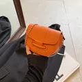 Vibrant orange pebble leather saddle bag with distinctive silver ball chain strap - Orange