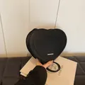 Close-up of heart-shaped black crossbody bag with rich rabbit letter embossing details - Black