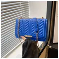 Detail of blue quilted shoulder bag with V-shaped stitching and gold chain strap - Blue