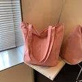 Rosa Nylon-Tragetasche mit breitem Schultergurt auf einem weißen Kunstbuch - Rosa