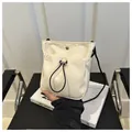 Detail van beige crossbody telefoontasje met zwart trekkoord en metalen sluiting - Wit