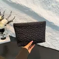 Chic black quilted clutch bag with floral embroidery and metallic zipper closure - Black