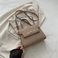 Sac à main kaki en cuir grainé avec fermoir doré sur fond de blazer beige et livre - Kaki
