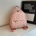 Pink mini backpack with rabbit print and metal bunny charm on white marble surface - No Pendant / Pink