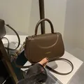 Deep brown leather vintage crossbody bag with a curved flap and gold fashion logo - Brown