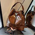 Glossy caramel brown drawstring bucket bag featuring a decorative metal butterfly charm - Tan