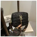 Detail of black quilted shoulder bag featuring gold hardware and stylish tassel charm - Black