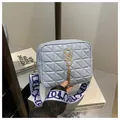 Detail view of quilted light blue crossbody bag with gold metal S logo and tassel charm - Blue