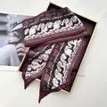 Detail of burgundy silk scarf featuring black cat and golden chain print in a gift box - Deep purple